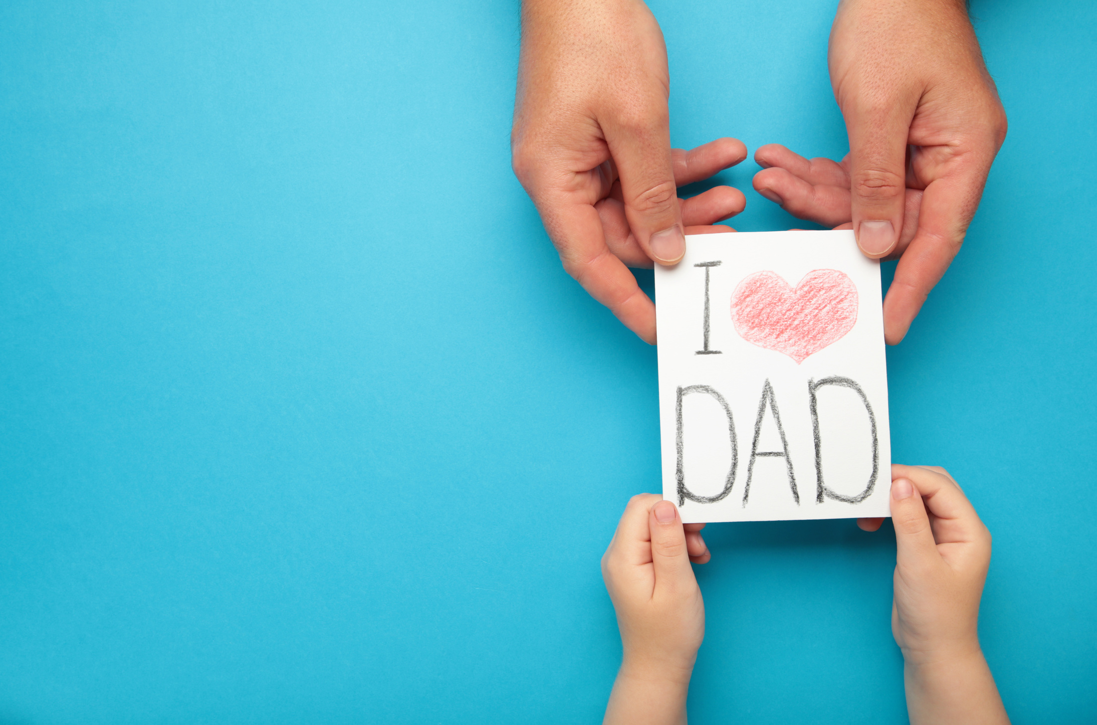 Father's Day. Child hands gives father's day greeting card to her father on blue background